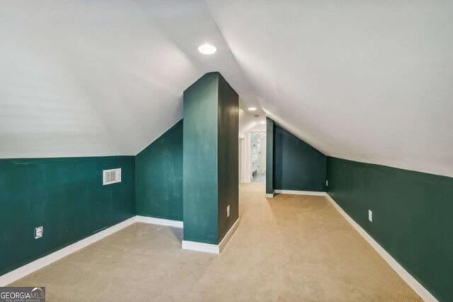 bonus room featuring light carpet and vaulted ceiling