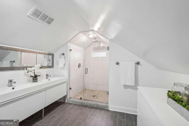 bathroom with vanity, wood-type flooring, vaulted ceiling, and walk in shower