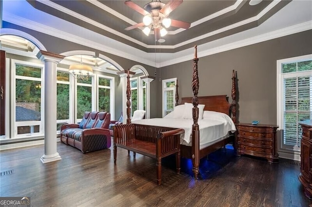 bedroom with ceiling fan with notable chandelier, dark wood-type flooring, a raised ceiling, decorative columns, and crown molding