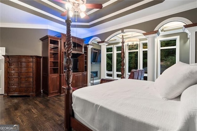 bedroom with dark wood-type flooring, a raised ceiling, ornate columns, crown molding, and ceiling fan with notable chandelier