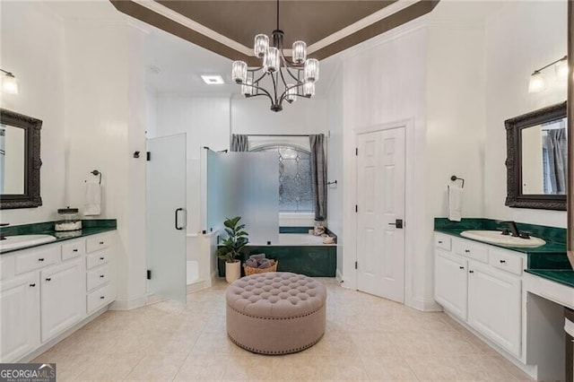 bathroom featuring tile patterned floors, vanity, ornamental molding, a notable chandelier, and a tray ceiling