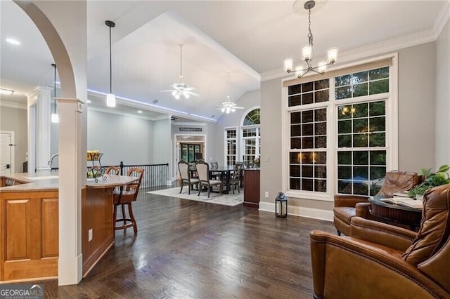 living room with ceiling fan with notable chandelier, vaulted ceiling, crown molding, and dark hardwood / wood-style flooring