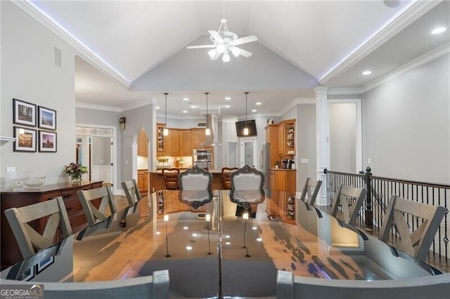 dining area with ceiling fan, decorative columns, crown molding, and vaulted ceiling