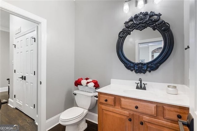 bathroom with toilet, vanity, and wood-type flooring