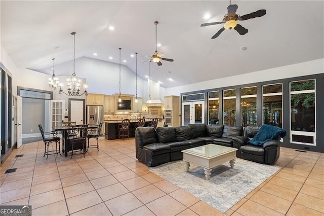 living room with ceiling fan with notable chandelier, high vaulted ceiling, and light tile patterned flooring