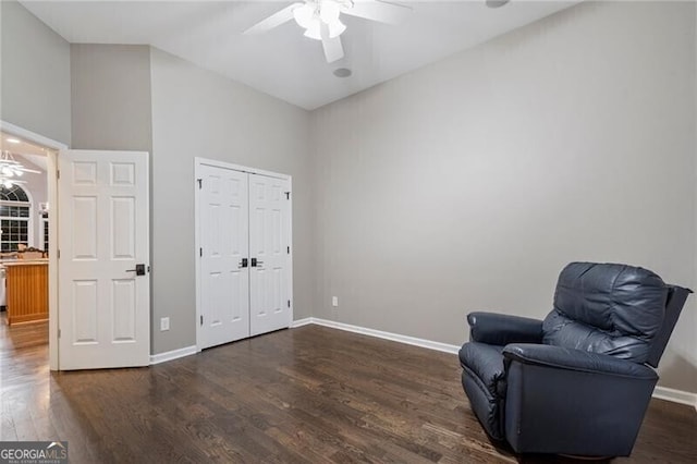 living area featuring a towering ceiling, dark wood-type flooring, and ceiling fan