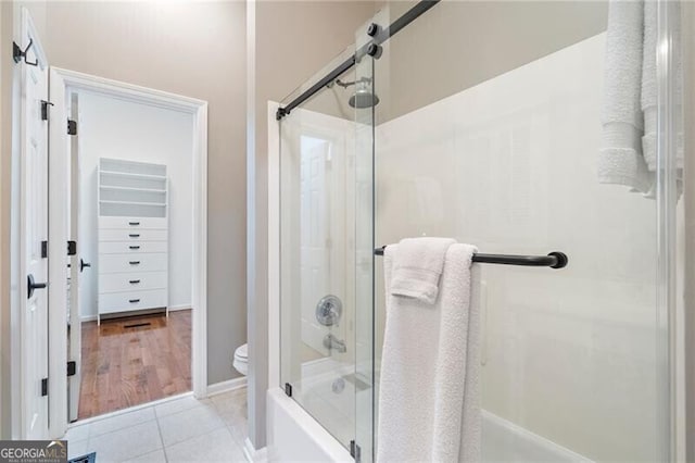 bathroom with toilet, enclosed tub / shower combo, and tile patterned floors