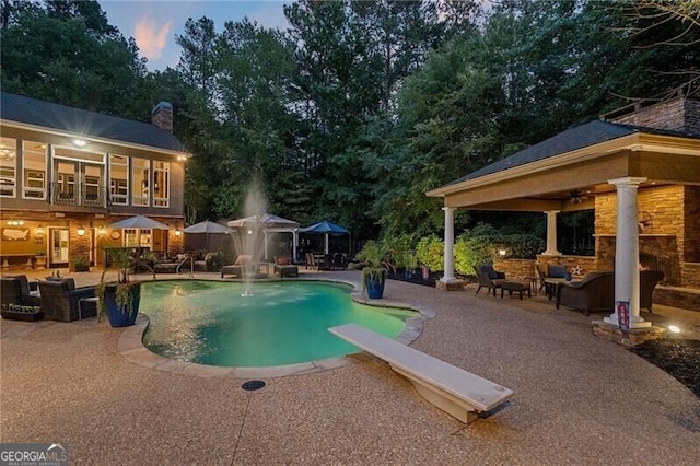 pool at dusk featuring a gazebo, an outdoor hangout area, a diving board, and a patio