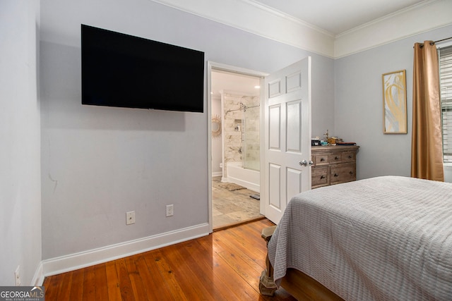 bedroom featuring connected bathroom, hardwood / wood-style flooring, and crown molding