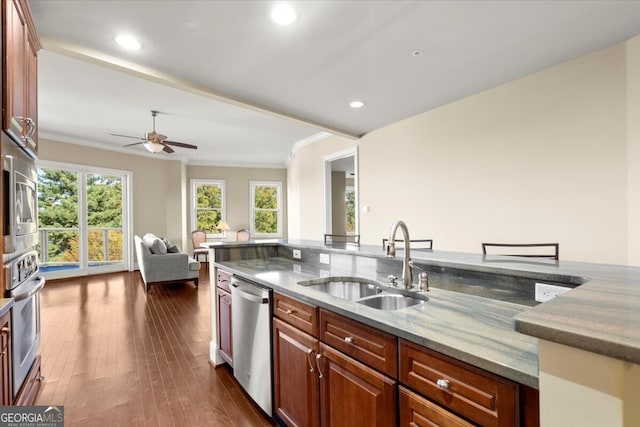 kitchen with sink, dark hardwood / wood-style floors, ornamental molding, stone countertops, and stainless steel appliances