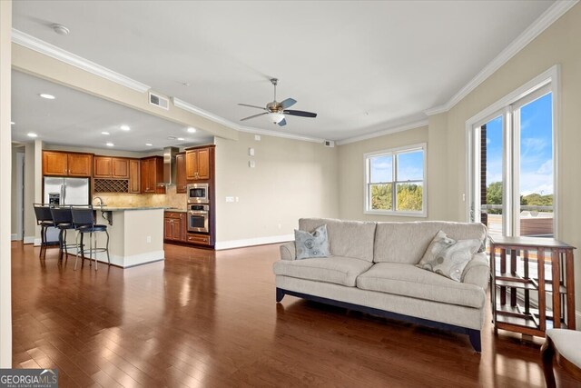 living room with crown molding, ceiling fan, and dark wood-type flooring