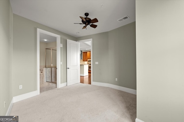 unfurnished bedroom featuring light carpet, ensuite bathroom, and ceiling fan