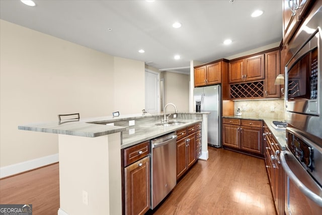 kitchen with light wood-type flooring, stainless steel appliances, sink, a large island with sink, and a breakfast bar area