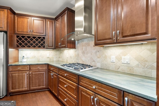 kitchen featuring appliances with stainless steel finishes, dark hardwood / wood-style floors, light stone counters, and wall chimney exhaust hood