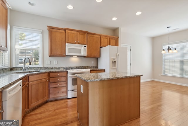 kitchen featuring light hardwood / wood-style floors, a kitchen island, white appliances, and sink