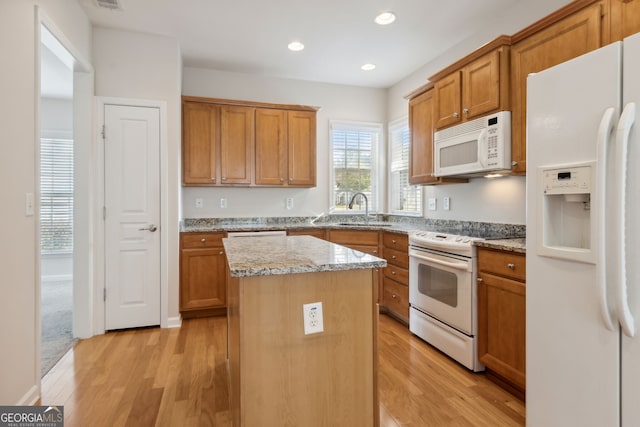 kitchen featuring light hardwood / wood-style floors, a kitchen island, white appliances, and sink