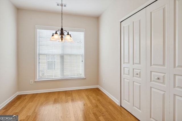 unfurnished dining area featuring hardwood / wood-style flooring and a chandelier