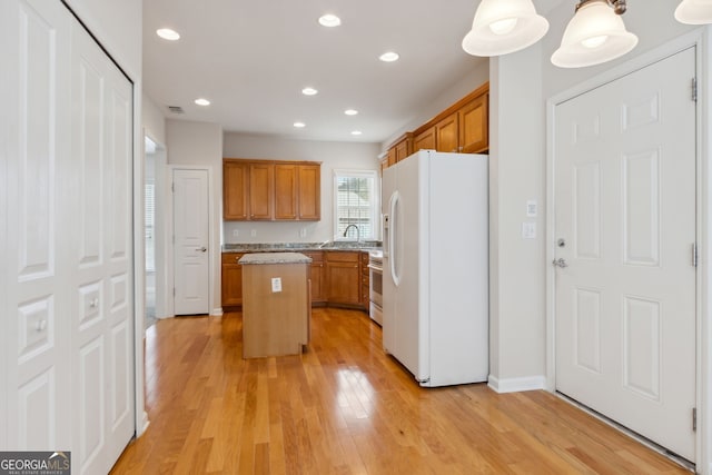 kitchen with sink, decorative light fixtures, light hardwood / wood-style floors, a kitchen island, and white fridge with ice dispenser