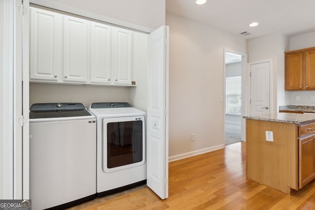 laundry room featuring cabinets, separate washer and dryer, and light hardwood / wood-style flooring