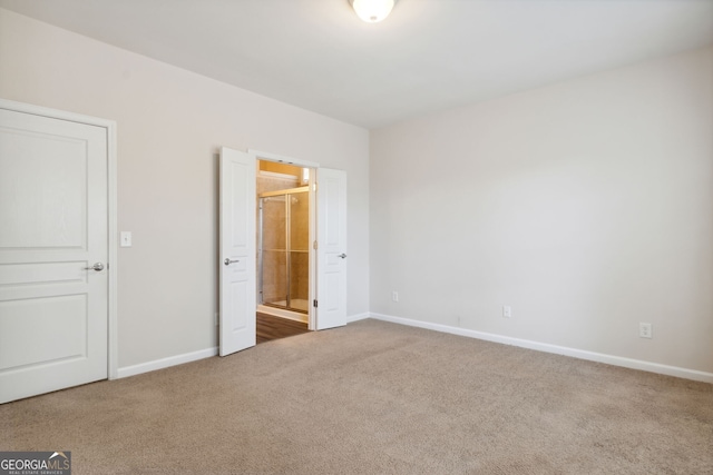 unfurnished bedroom featuring ensuite bath and carpet