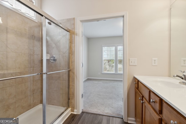 bathroom with hardwood / wood-style floors, vanity, and a shower with door