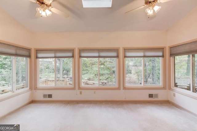 unfurnished sunroom featuring ceiling fan, a healthy amount of sunlight, and a skylight