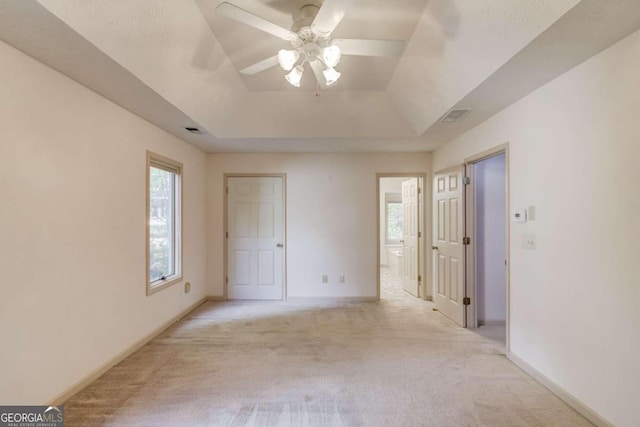 carpeted spare room featuring a tray ceiling and ceiling fan