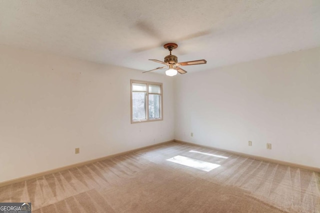 carpeted spare room featuring ceiling fan and a textured ceiling