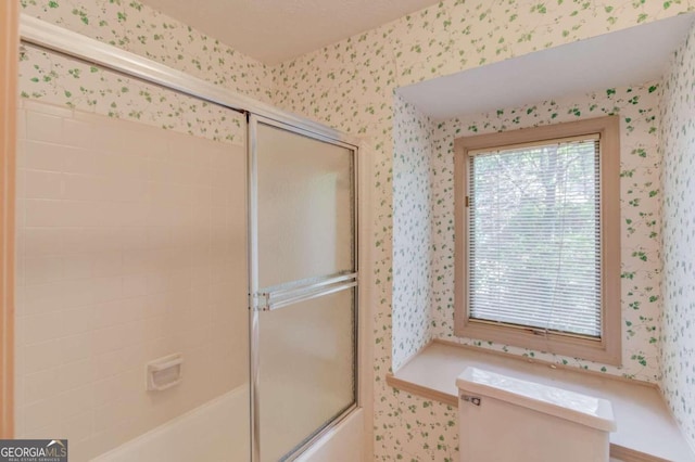 bathroom with enclosed tub / shower combo and toilet