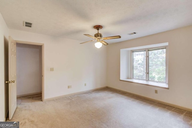 carpeted spare room featuring ceiling fan and a textured ceiling