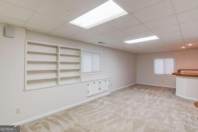 basement with a drop ceiling and light carpet