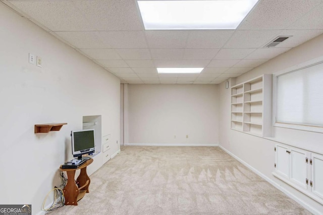 interior space with a drop ceiling and light colored carpet