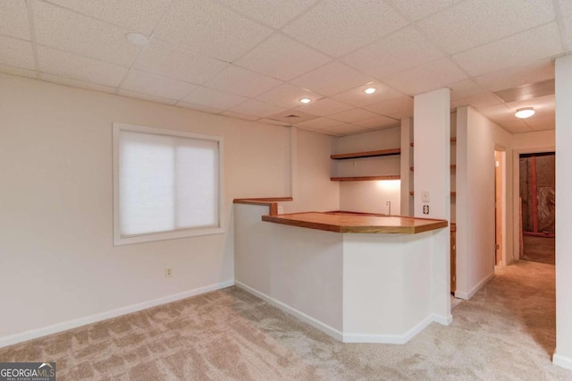 kitchen with a paneled ceiling, light colored carpet, and kitchen peninsula