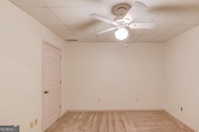 empty room featuring a paneled ceiling, ceiling fan, and light colored carpet