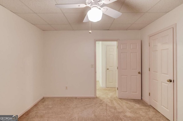 carpeted empty room featuring ceiling fan and a drop ceiling