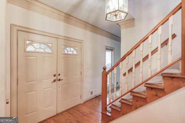 entryway with a wealth of natural light, hardwood / wood-style floors, and crown molding