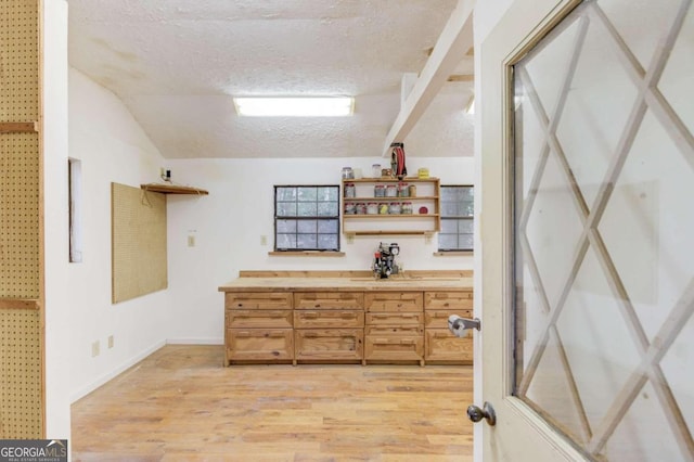 interior space featuring vaulted ceiling, light hardwood / wood-style floors, and a textured ceiling