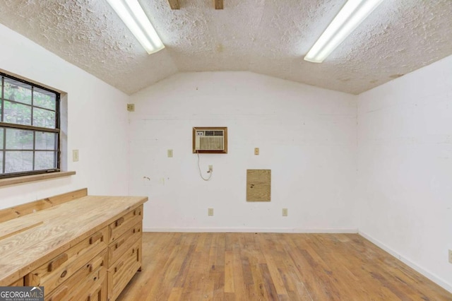 laundry area featuring a wall mounted AC, light hardwood / wood-style flooring, and a textured ceiling