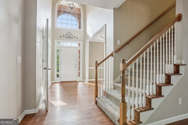 entrance foyer featuring a towering ceiling and light wood-type flooring