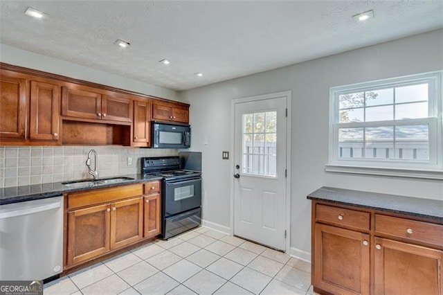 kitchen with black appliances, sink, decorative backsplash, dark stone countertops, and light tile patterned floors