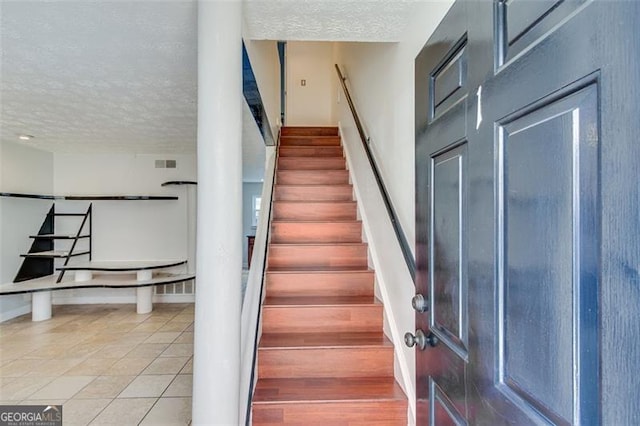 stairs featuring tile patterned floors and a textured ceiling