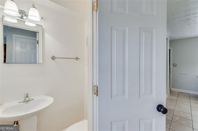 bathroom featuring a textured ceiling, tile patterned floors, and sink