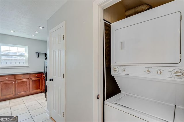 laundry room with stacked washing maching and dryer and light tile patterned flooring