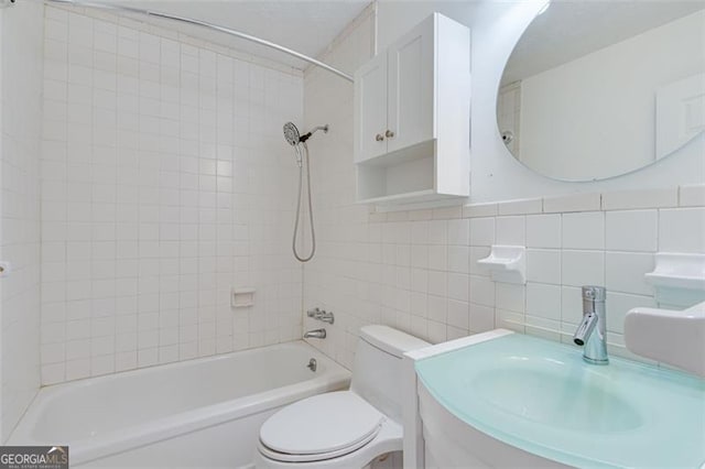 full bathroom with tile walls, vanity, tiled shower / bath combo, and toilet