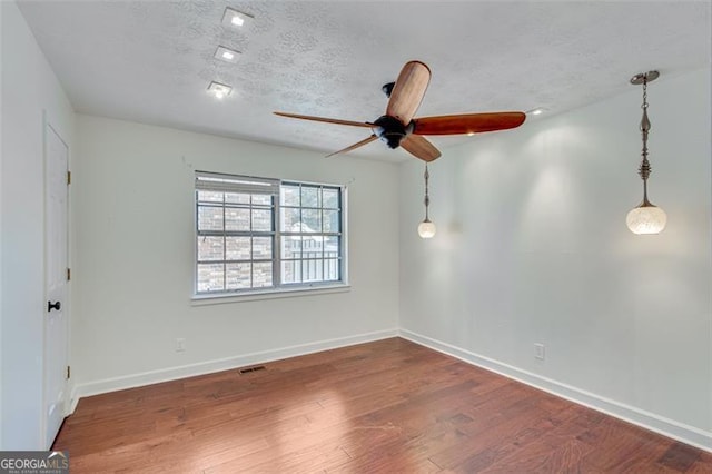 unfurnished room with ceiling fan, dark wood-type flooring, and a textured ceiling