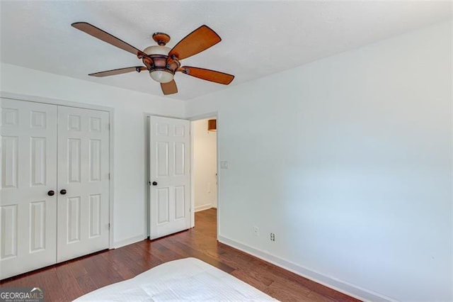 unfurnished bedroom with a closet, ceiling fan, and dark wood-type flooring