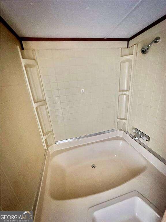 bathroom with crown molding, a textured ceiling, and tiled shower / bath