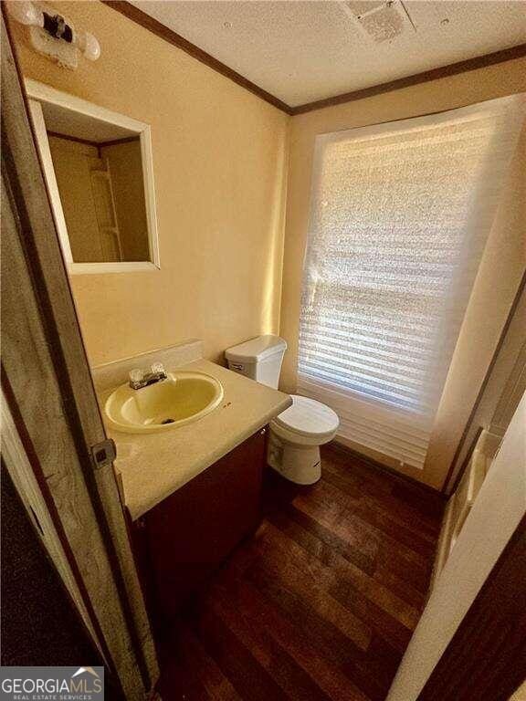 bathroom featuring crown molding, hardwood / wood-style floors, a textured ceiling, toilet, and vanity