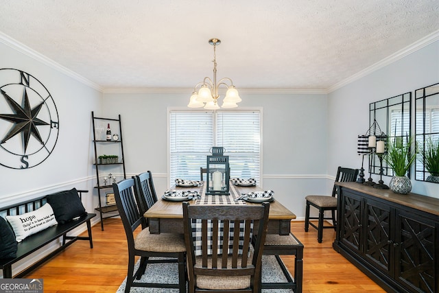 dining room with a textured ceiling, light hardwood / wood-style floors, crown molding, and a notable chandelier