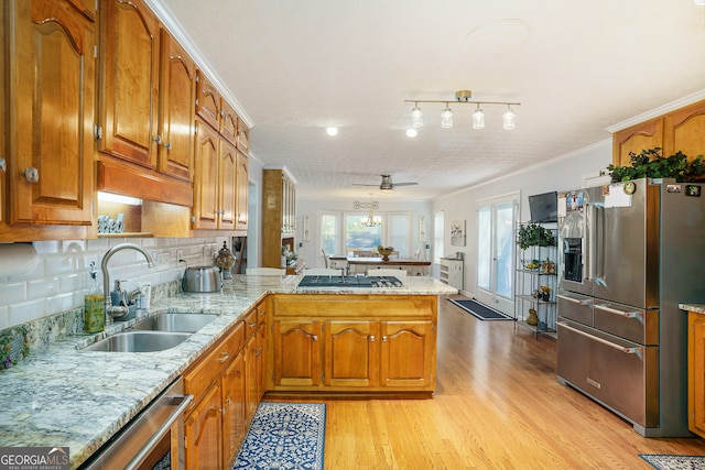 kitchen featuring kitchen peninsula, appliances with stainless steel finishes, ceiling fan, crown molding, and light hardwood / wood-style floors